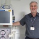 Image shows a man standing alongside a dialysis machine.