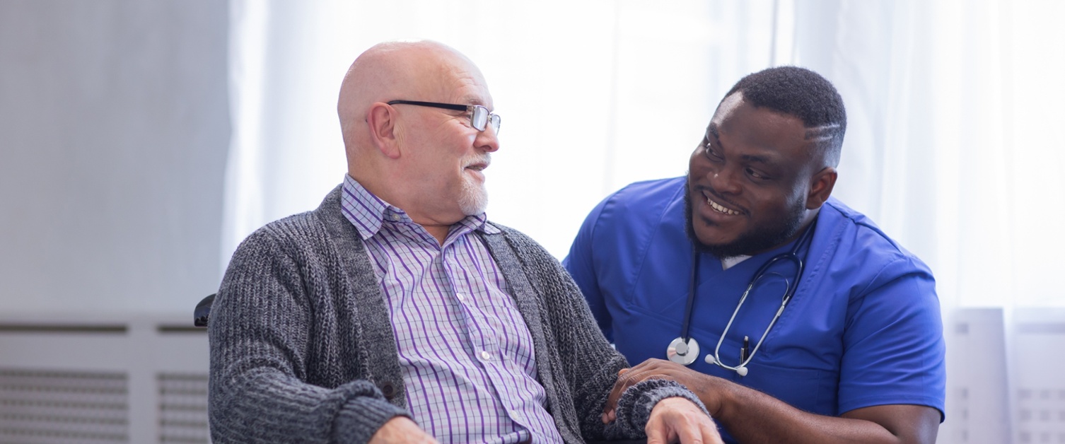 A nurse talks to a patient in a wheelchair.