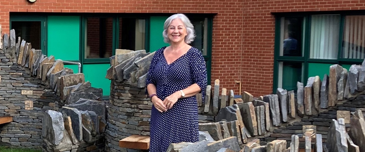 Image shows a woman standing next to some bricks