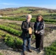 Image shows a man and woman holding awards in a field