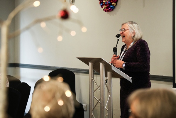 Image shows a speaker giving a presentation at an event.