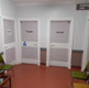 Image shows 3 coloured chairs in a corridor along the walls surrounded by 4 audiology room doors.