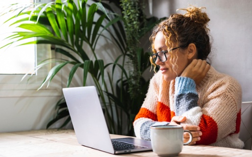 Image shows a woman using a laptop.