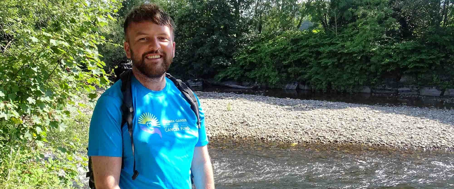 Image shows man standing near a river.