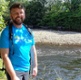 Image shows man standing near a river.