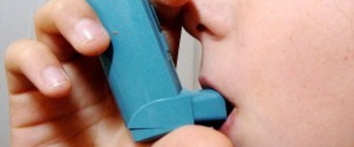 A child inhaling from a blue asthma pump
