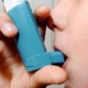 A child inhaling from a blue asthma pump