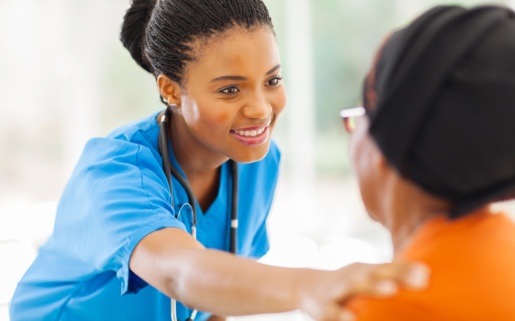 A nurse smiles at and comforts a patient