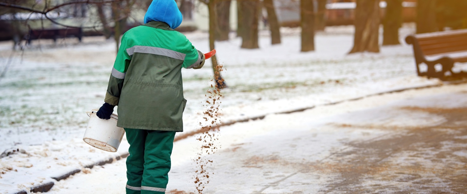 A person spreads grit on an icy road