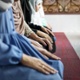 Women in head scarves kneel to pray.
