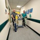 Image shows two men in a hospital corridor standing behind a machine and gas cylinder