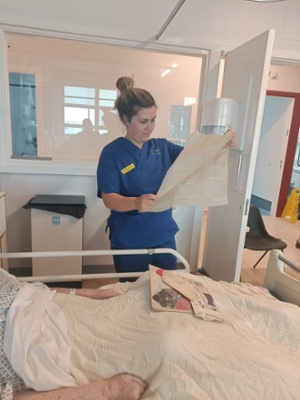 Image shows a woman reading an old newspaper