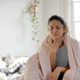A woman sat on a bed with a sore throat