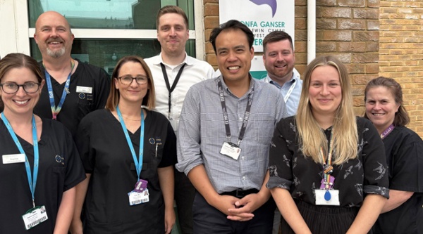 Image shows a group of clinicians outside a hospital building.