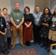 Seven members of staff from the Department of Liaison Psychiatry, stand in a office, smiling at the camera.