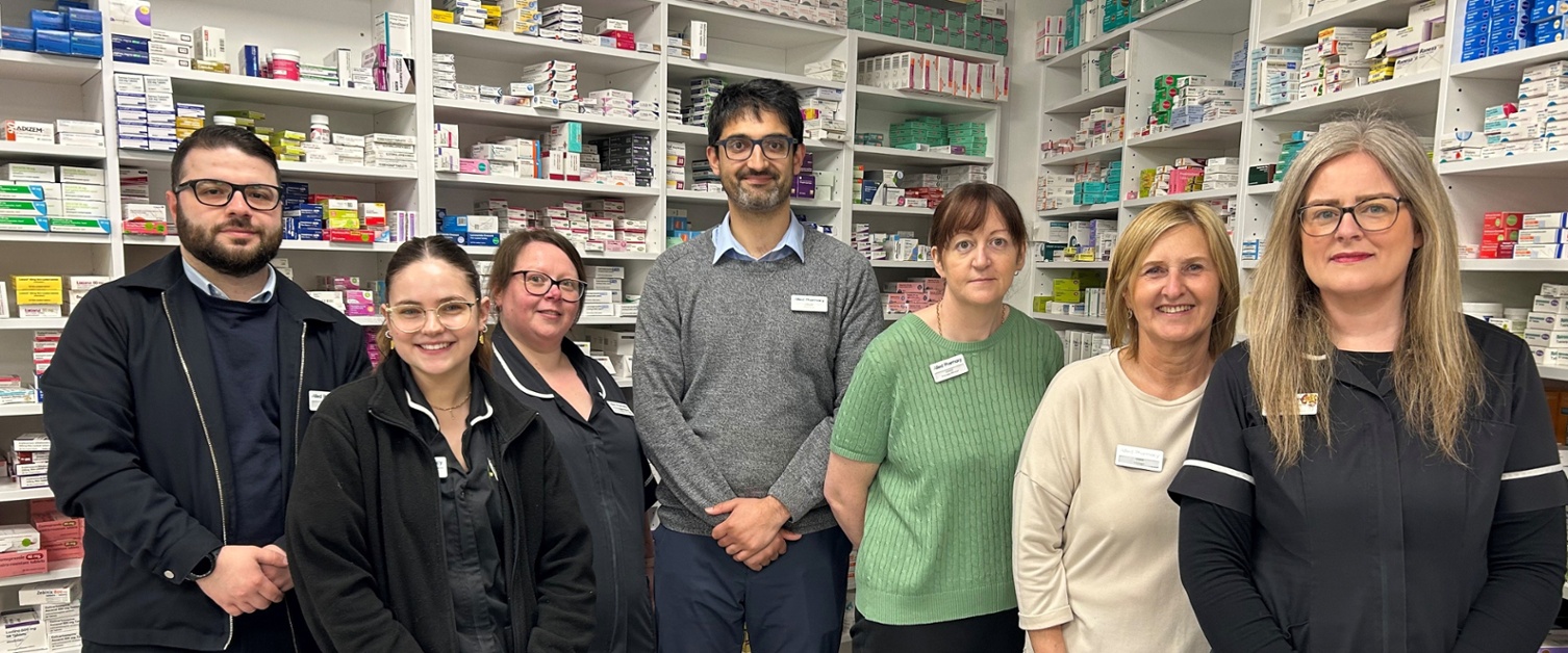 Members of staff from Allied Pharmacy stood in front of the medicine cabinet