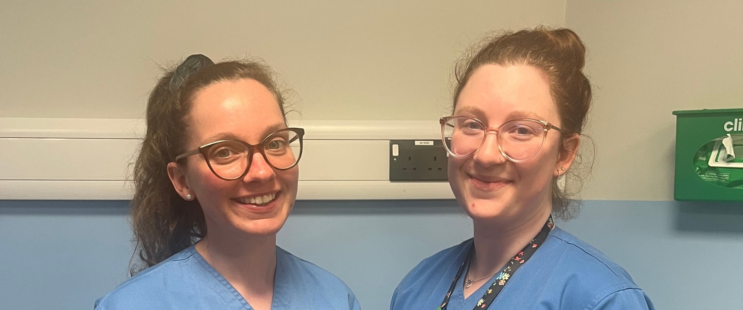 Image shows two clinicians standing in a patient bay