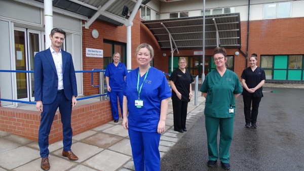 Image shows a group of staff outside a hospital