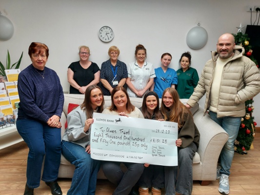 Image shows a group of people and a cheque