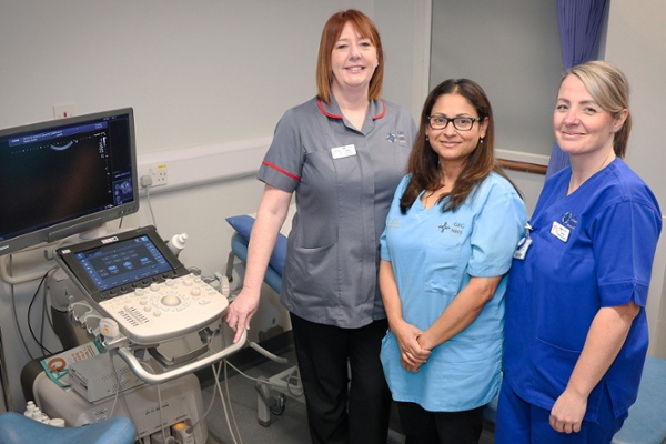 Image shows three clinicians in a hospital sonography room.