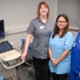 Image shows three clinicians in a hospital sonography room.