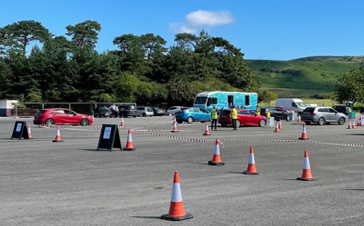 Photo shows a car park with cones set up to mark three lanes. The Immbulance is parked nearby.