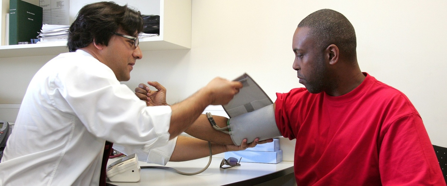 A GP seated left takes a patient