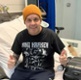 A man sitting on a hospital bed, making a thumbs-up gesture