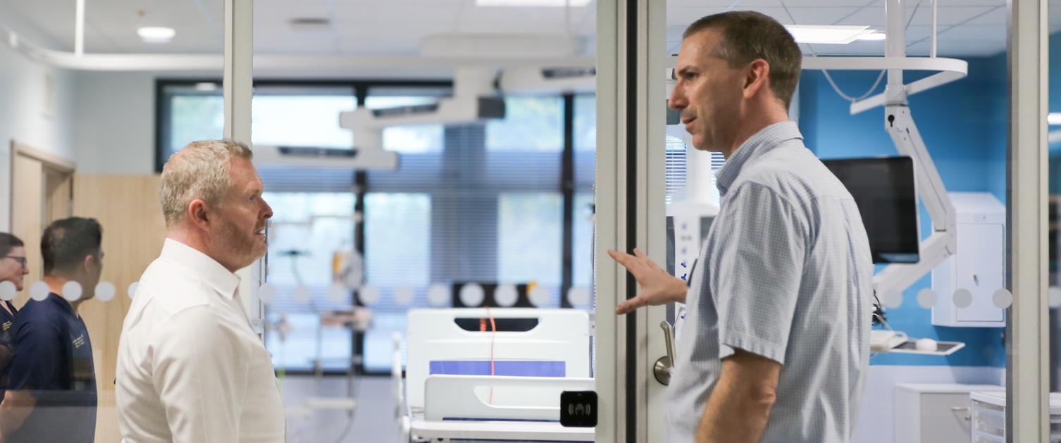 A doctor explains equipment in a brand new hospital room to a politician