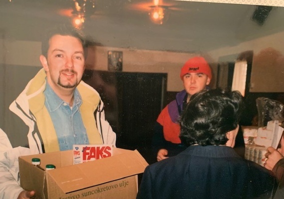 Image shows a man holding a cardboard box