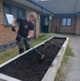 Image shows a man raking soil