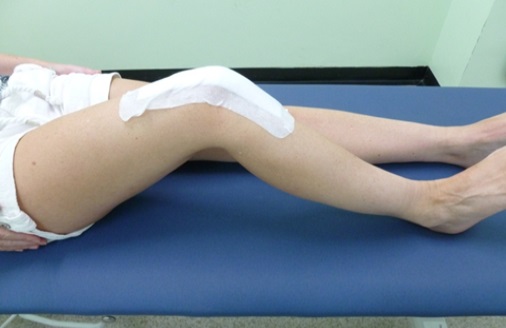 A patient lies on a bed. Their right leg is bent at the knee.