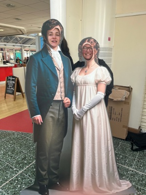 Image shows two people standing in a cardboard cut out