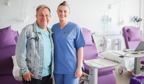 Image shows a patient and a nurse in a hospital room.