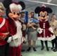 Mickey and Minnie Mouse, standing alongside a family and baby