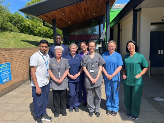 Image shows a group of people standing outside of a hospital entrance
