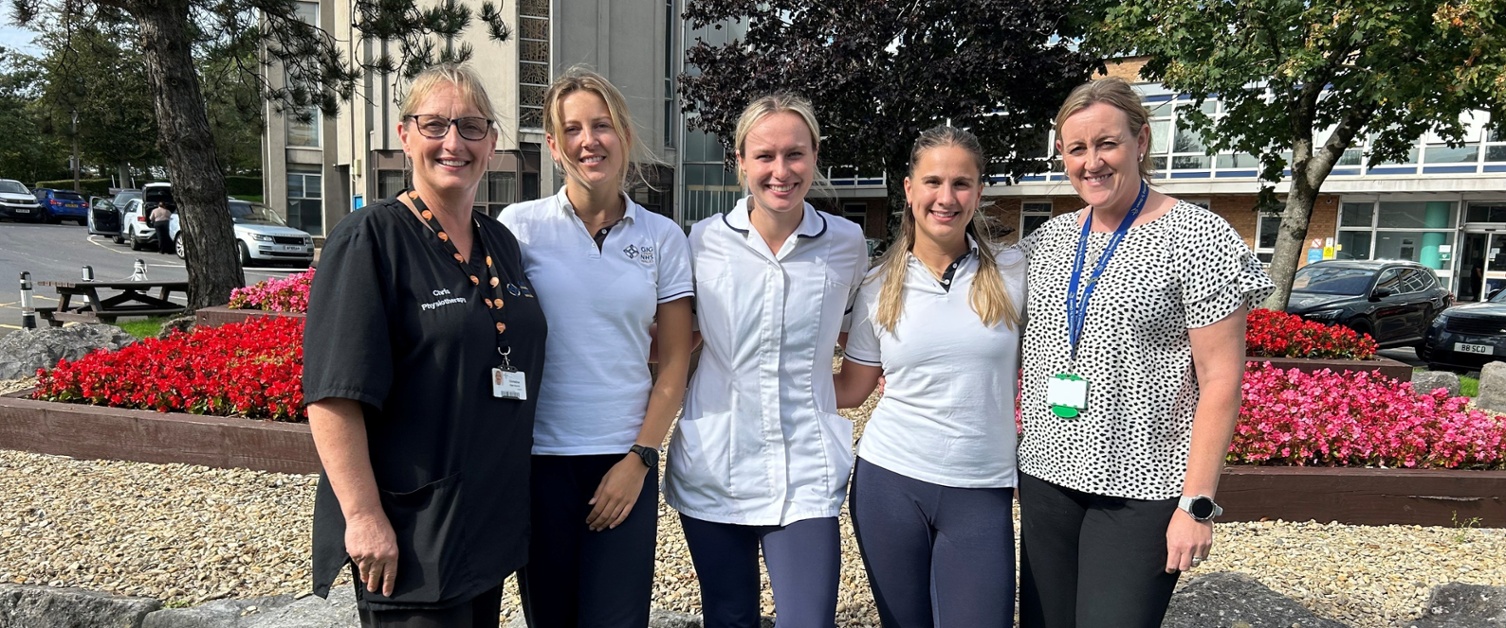 Members of the physiotherapy team stood in front of flowers