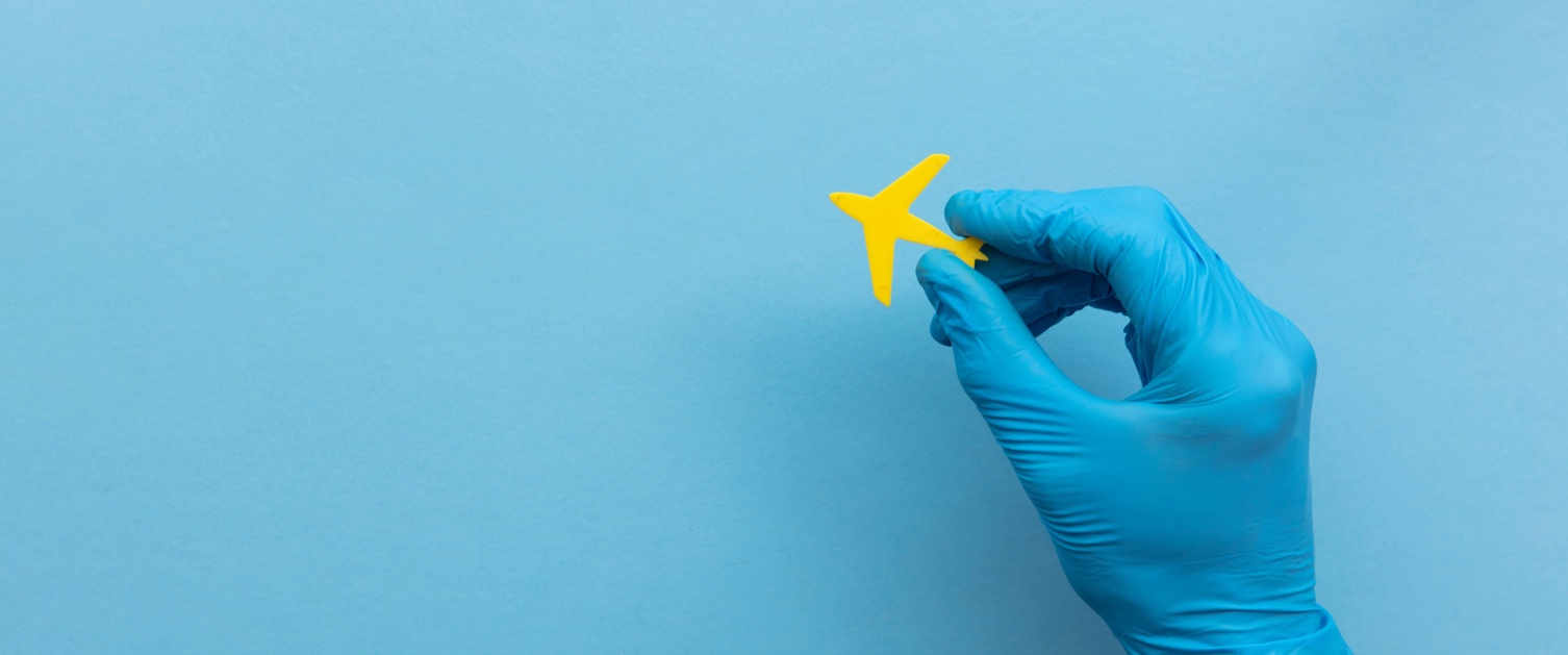 A hand in a clinical glove holds a small toy jet plane.