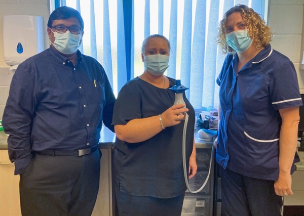 A man and two women wearing masks inside a GP surgery