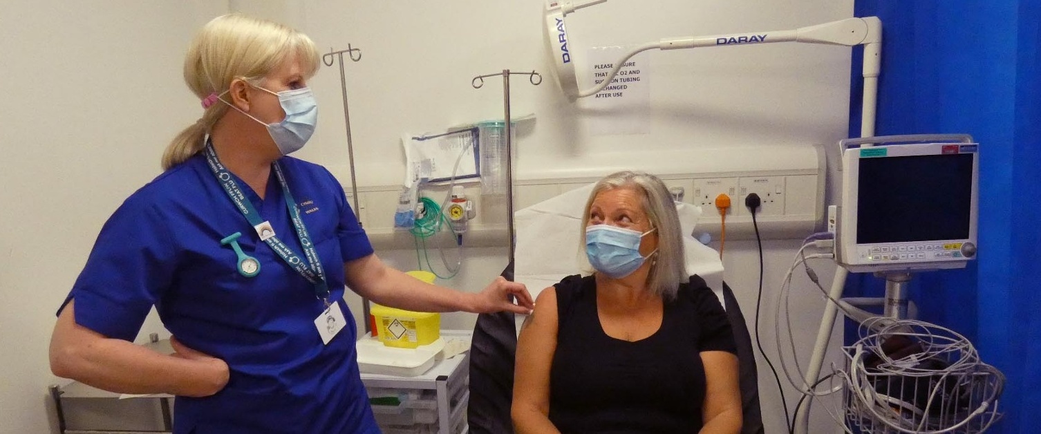 Nurse Cath Courts standing next to Alison Holland lying on trolley.