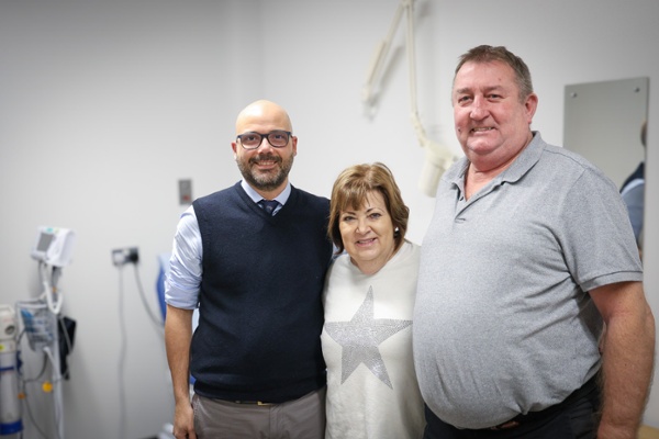 Image shows two men and a woman standing