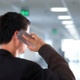 A man on the phone in an empty hospital corridor, facing away from the camera.