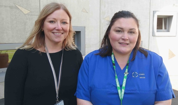 Image shows a doctor and a nurse outside a hospital building