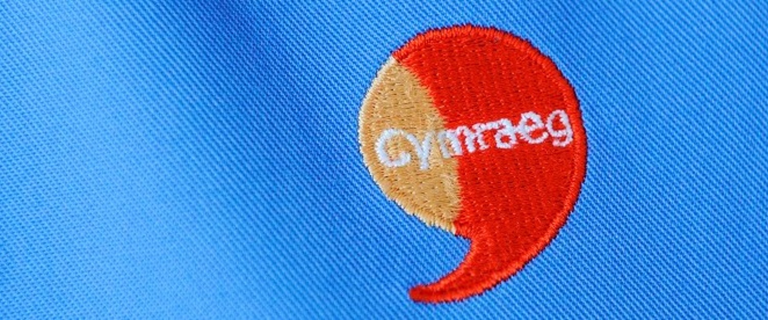 An image with the word Cymraeg embroidered into a speech bubble.