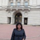Image shows a woman standing in front of Buckingham Palace