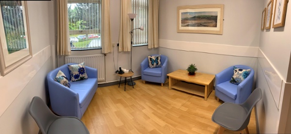 Hospital quiet room with blue sofa and chairs and light soft furnishings