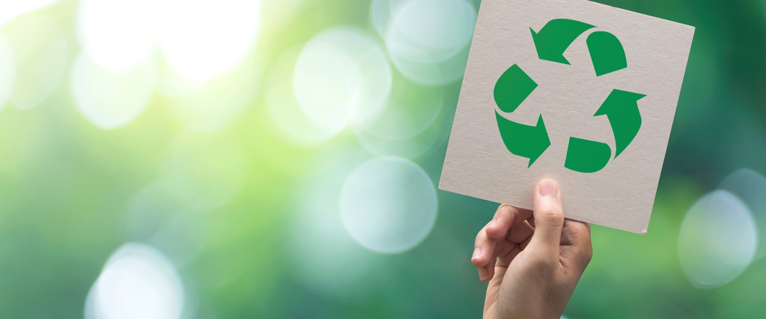 Image shows a hand holding up a recycling logo