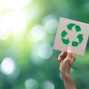 Image shows a hand holding up a recycling logo