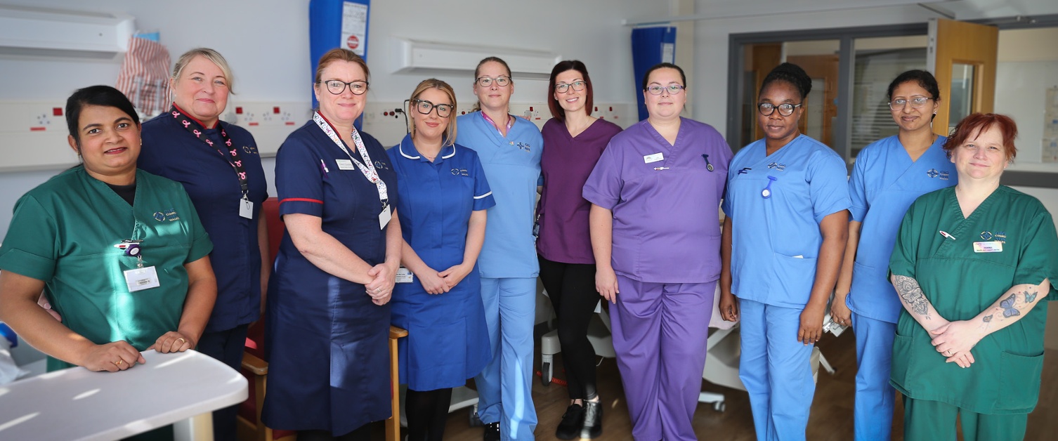 A group of assorted hospital staff posing for a photograph in a wardd