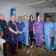 A group of assorted hospital staff posing for a photograph in a wardd